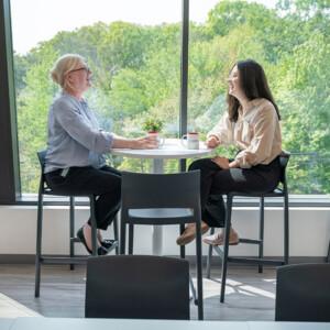 Two female Keros Therapeutics employees having a discussion at a high top table